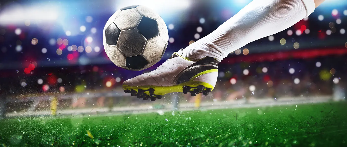 football scene at night match with close up soccer boot hitting ball with power